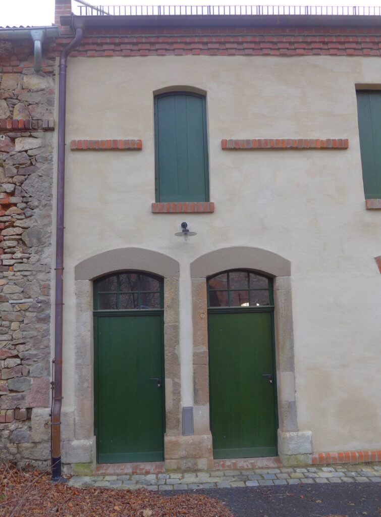 Fassade des Stallgebäudes mit historischen Türen und Fenstern.